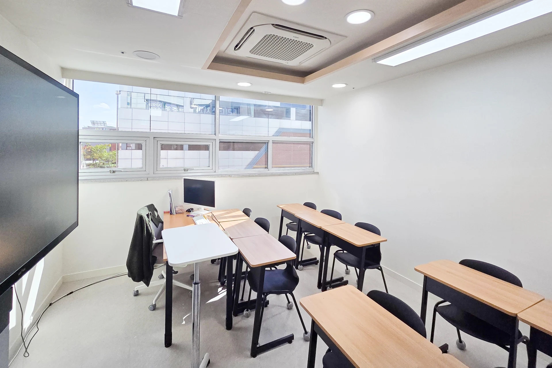 교실 앞 대형 화면과 강사 책상, 학생 책상 및 창문