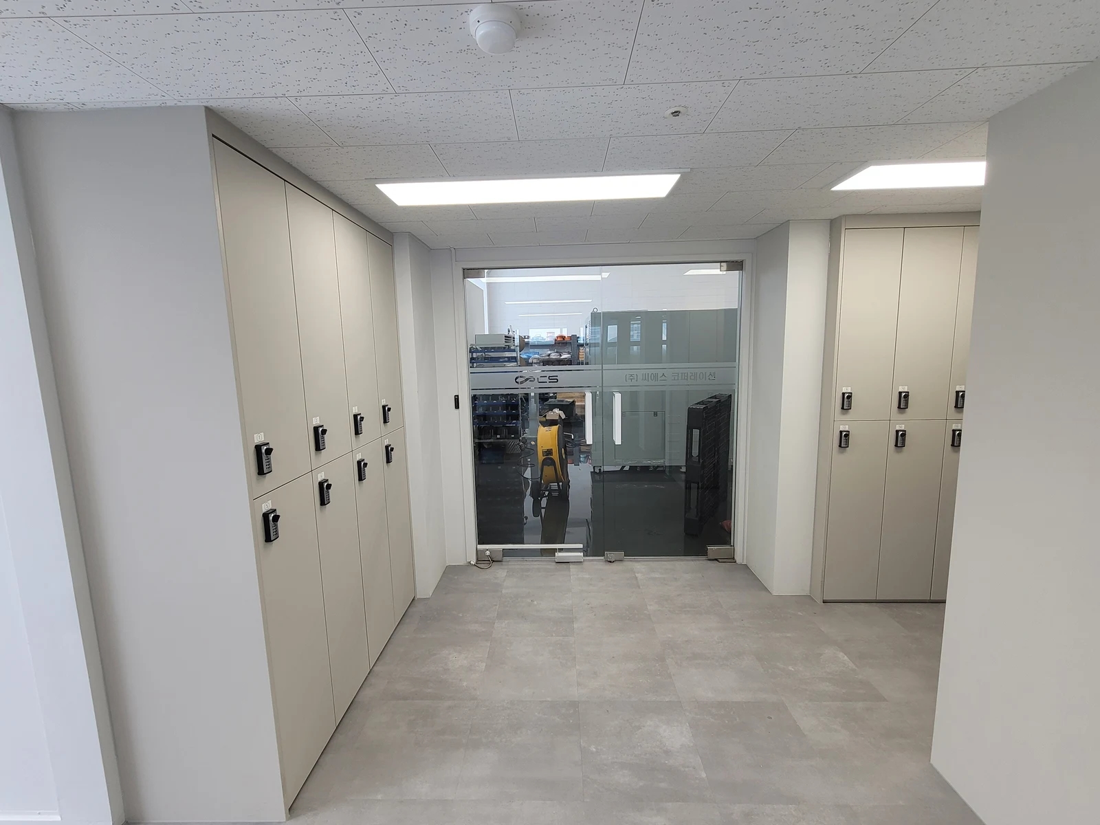 양쪽 벽을 따라 잠금장치가 달린 긴 수납장 문과 낮은 문이 나뉘어 있는 공간