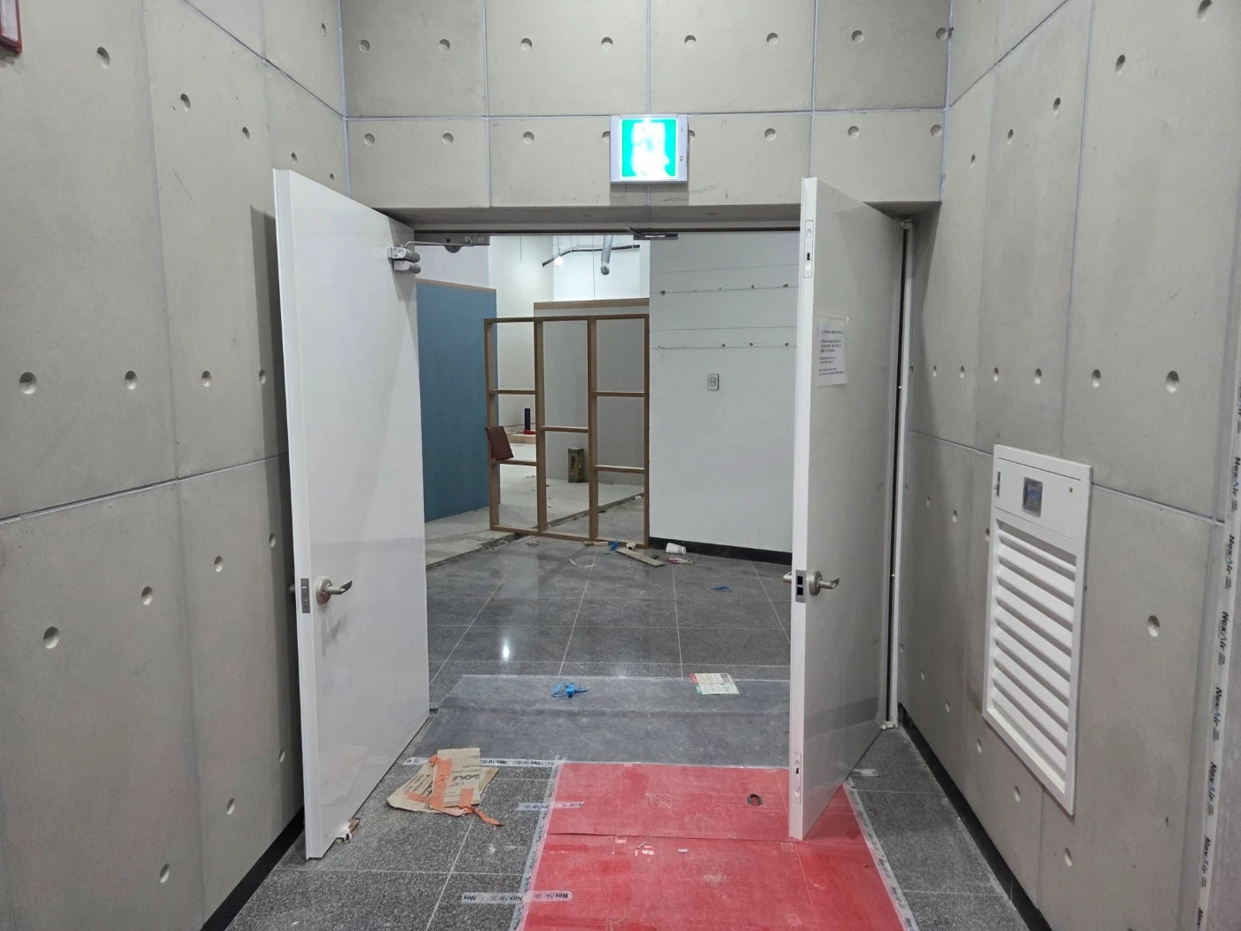 양쪽 문이 열린 출입구 너머로 바닥과 공사 중 내부가 보이는 모습