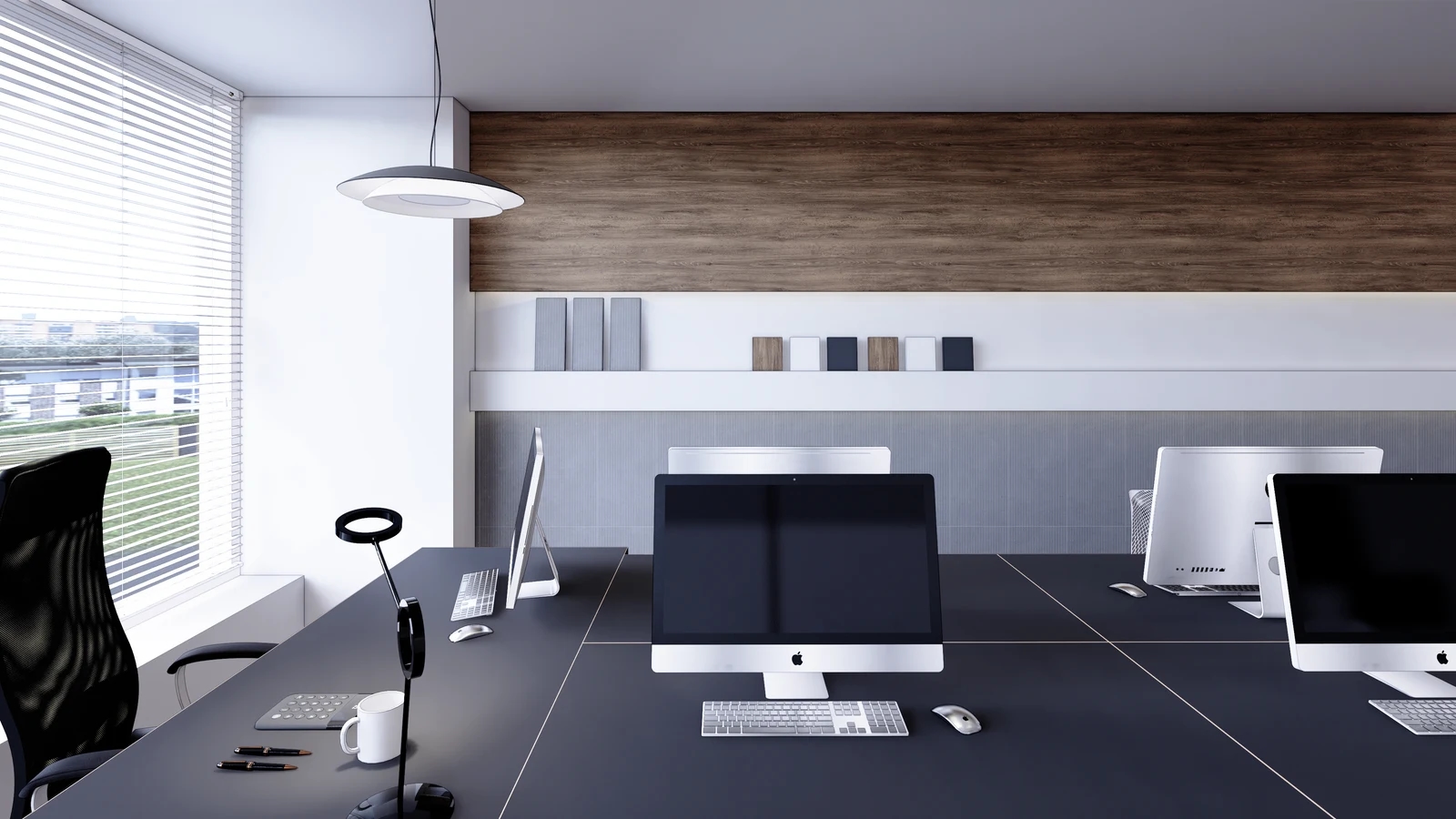 An office design with monitors, desks, chairs and a low sill beside a window with white blinds