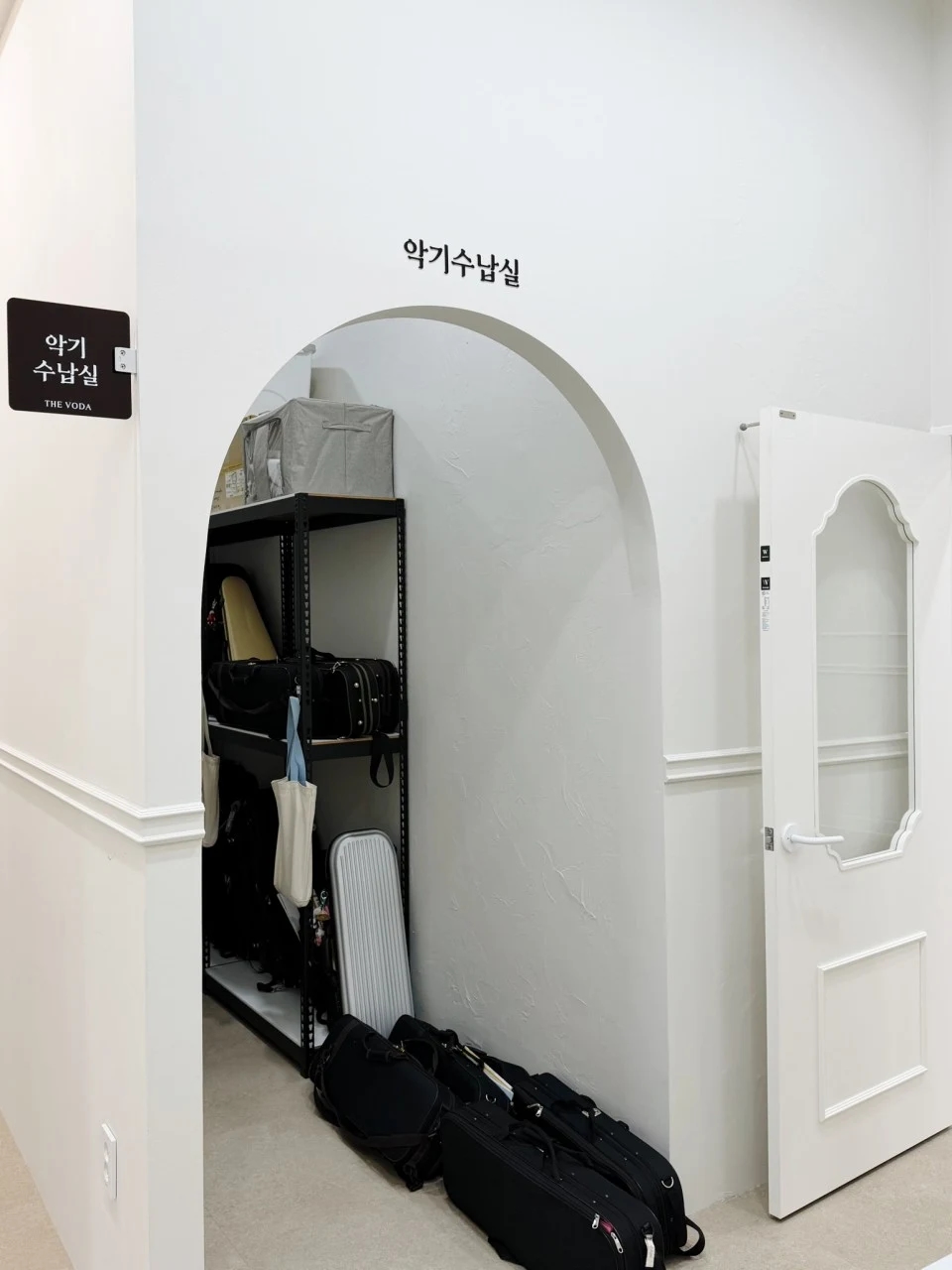 악기수납실 표지 아래 선반과 바닥에 놓인 여러 악기 케이스