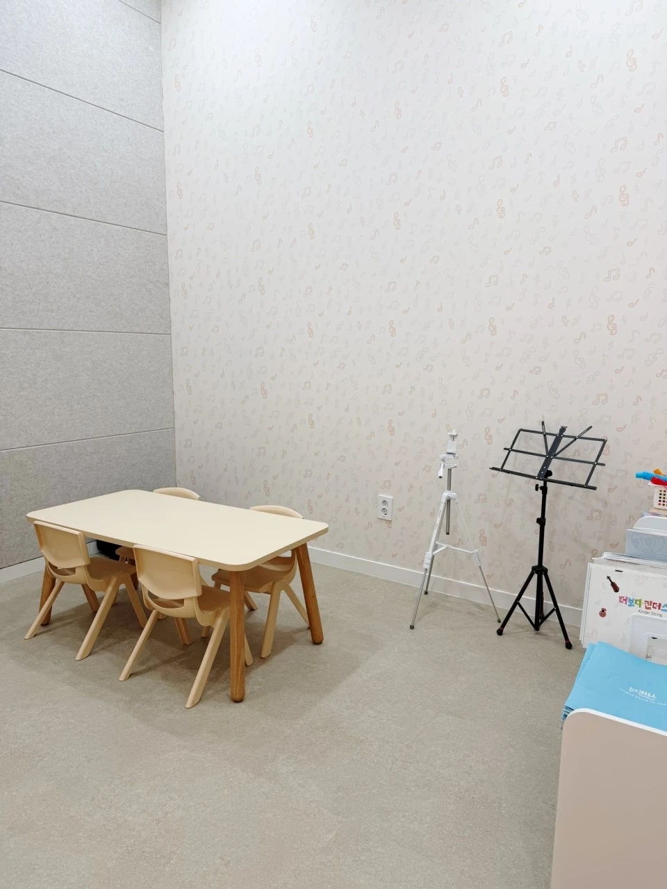 낮은 테이블과 의자, 두 개의 악보대가 놓인 음악학원 레슨실