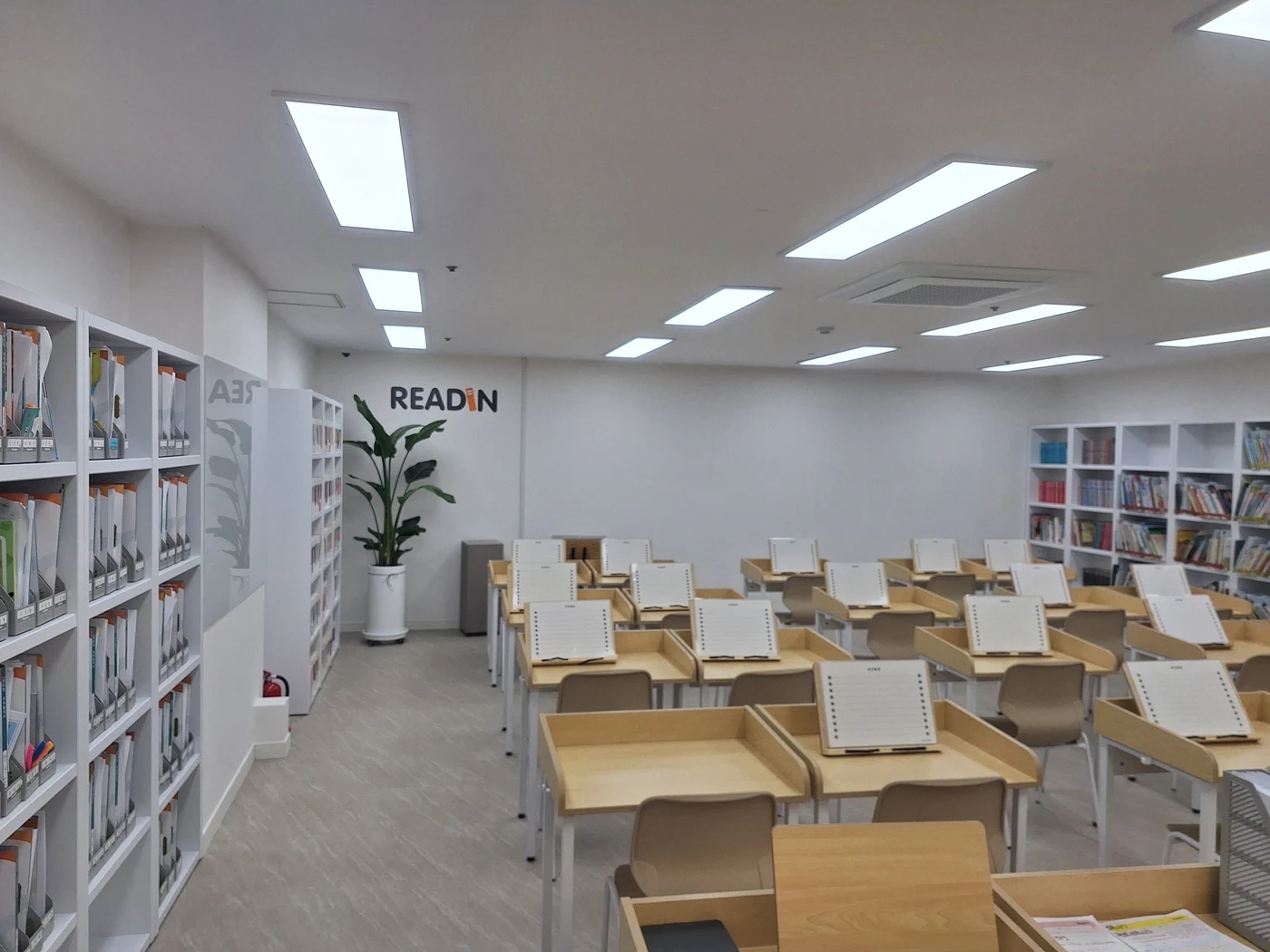 독서논술학원의 수업 책상 양쪽 벽을 따라 책장이 놓인 교실 전경