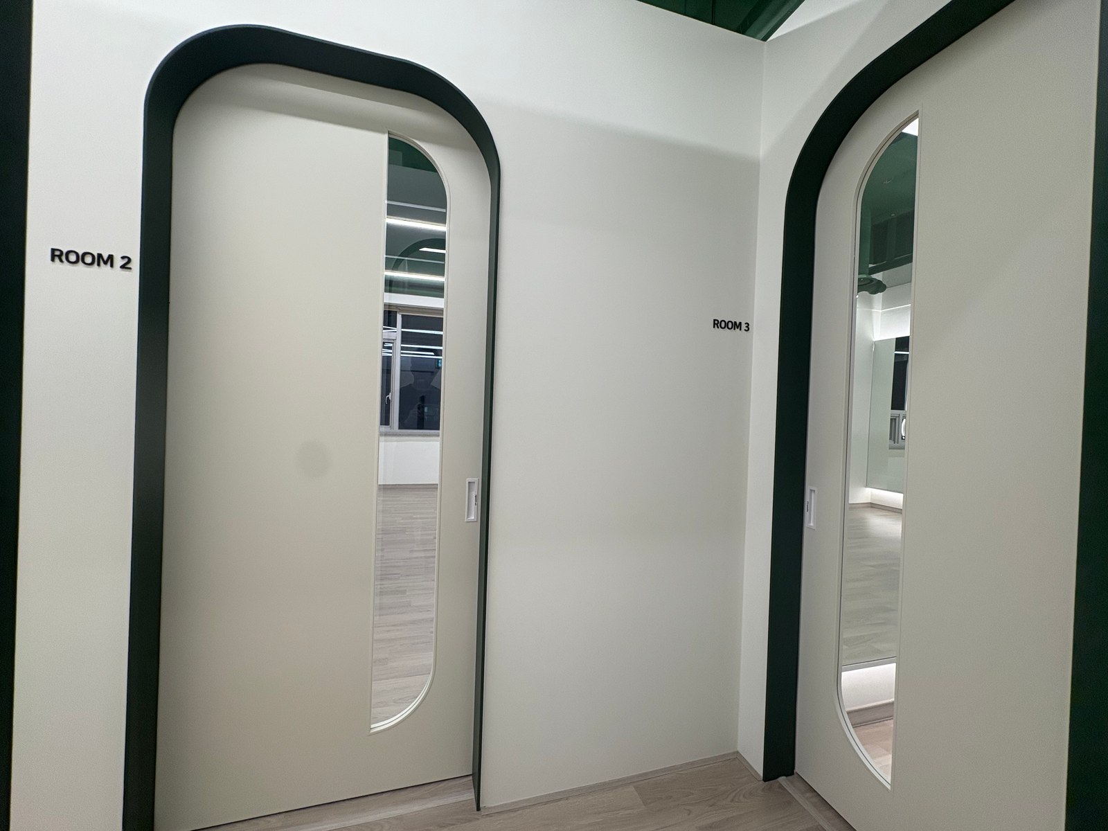 짙은 초록색 문틀과 ROOM 2, ROOM 3 표지가 있는 요가원 수업실 문